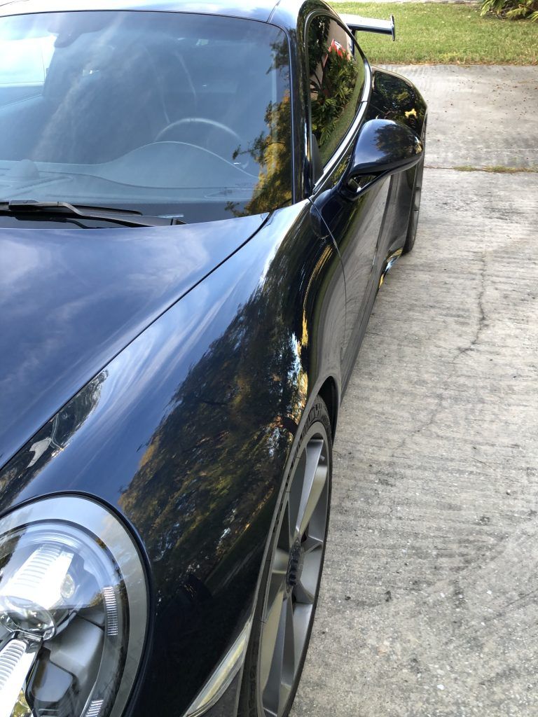 A black sports car is parked in a driveway.