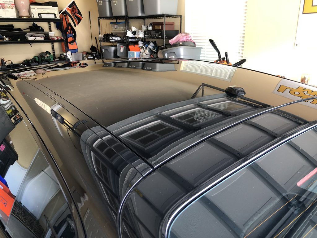 A car with a roof rack is parked in a garage.