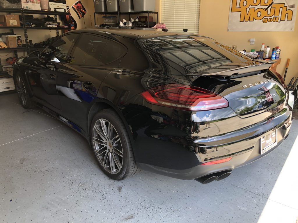 A black porsche panamera is parked in a garage.