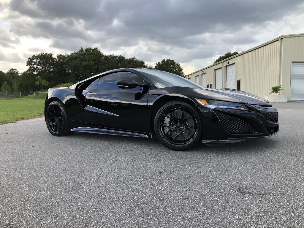A black sports car is parked in front of a building.