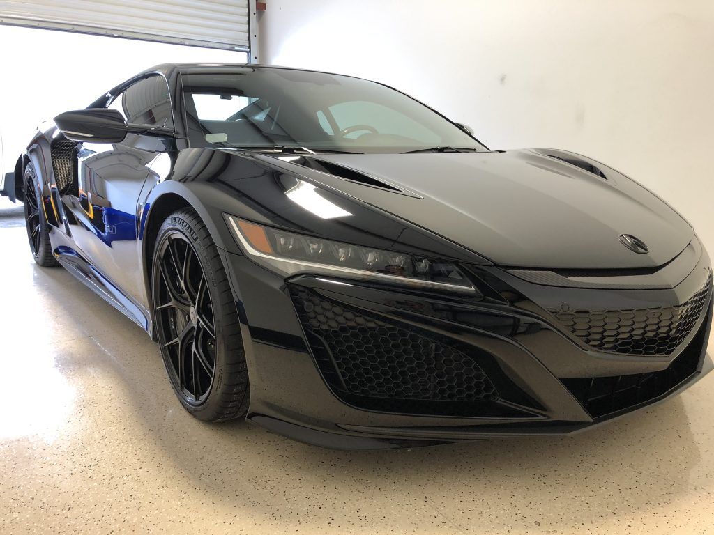 A black sports car is parked in a garage.