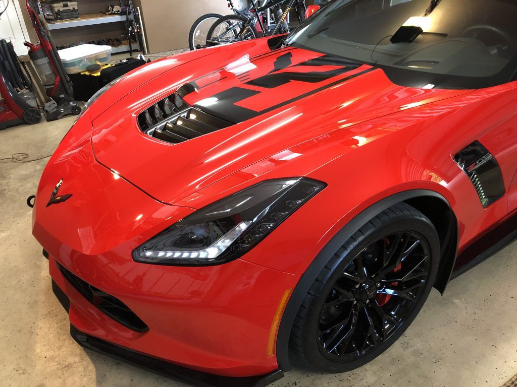 A red sports car with black wheels is parked in a garage.