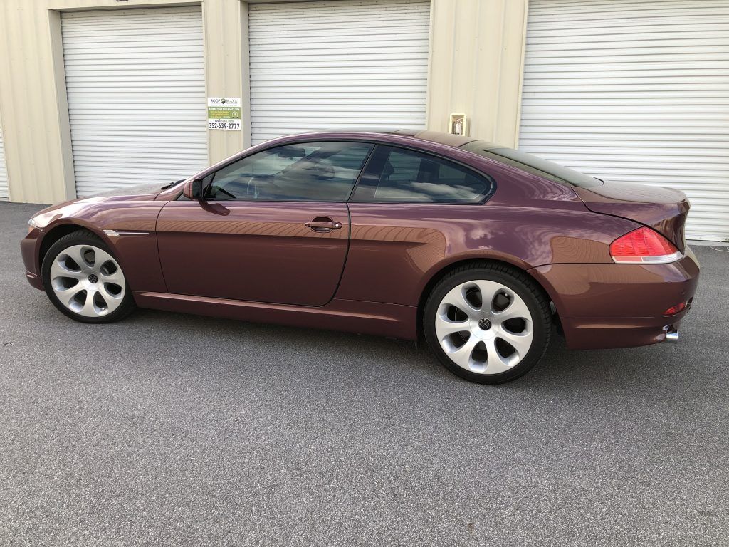 A brown bmw is parked in front of a garage door.
