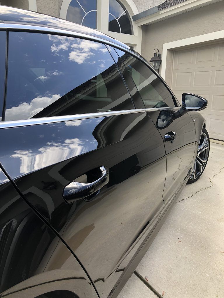 A black car is parked in front of a garage door.