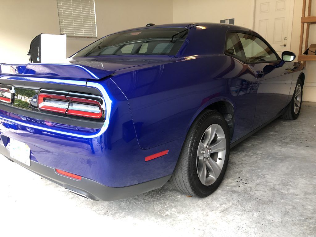 A blue dodge challenger is parked in a garage.
