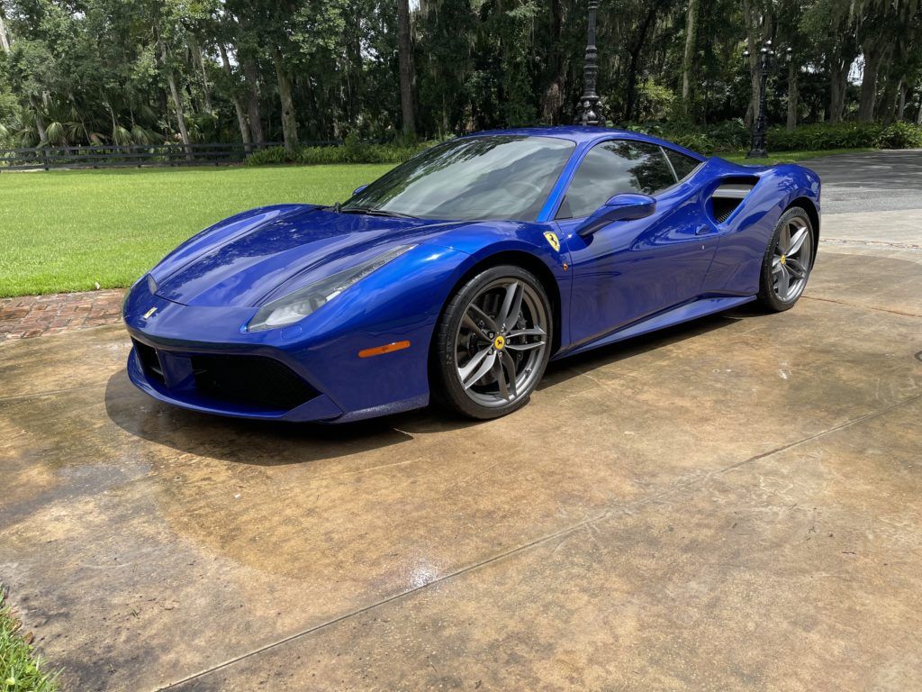 A blue ferrari 488 gtb is parked in a driveway.