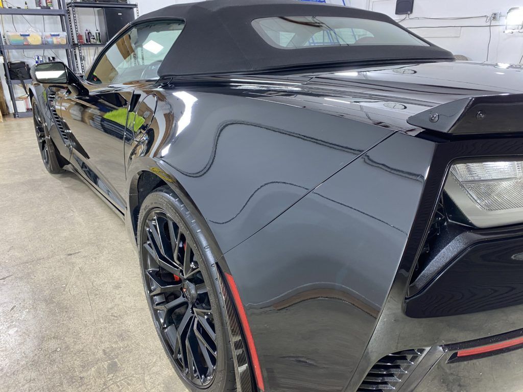 A black convertible sports car is parked in a garage.
