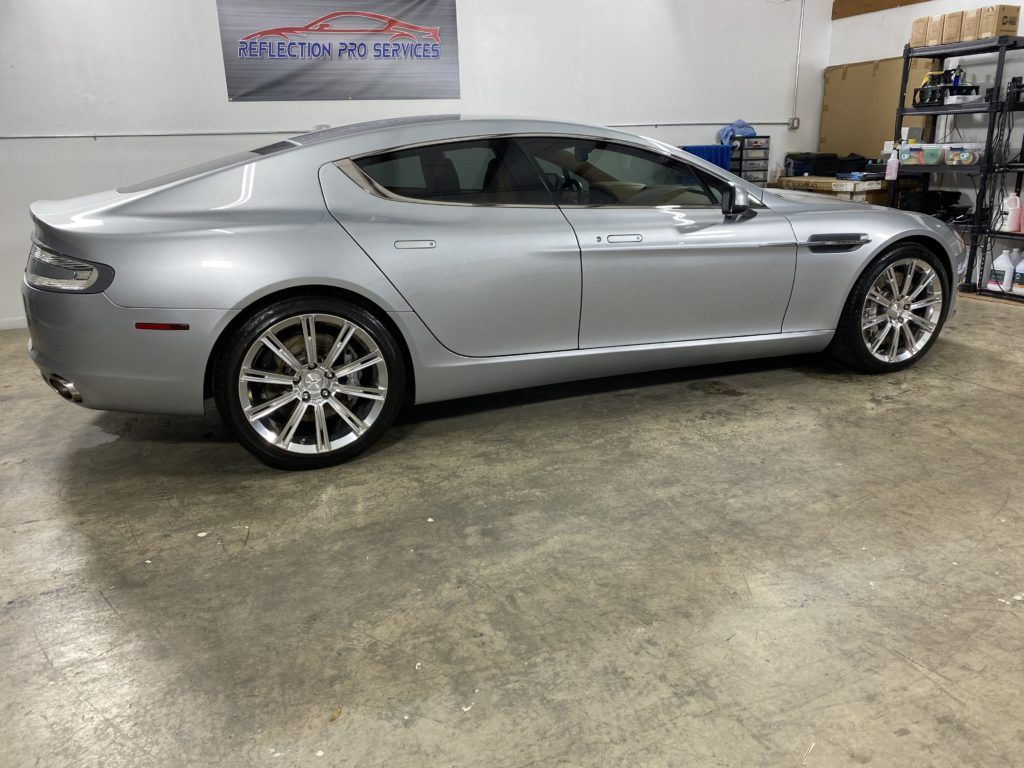 A silver aston martin sports car is parked in a garage.