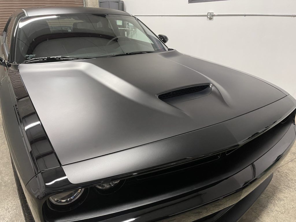 A black dodge challenger is parked in a garage.