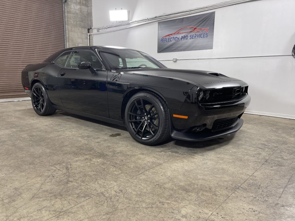 A black dodge challenger is parked in a garage.