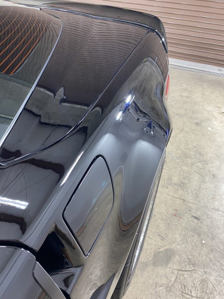 A close up of a black car parked in a garage.