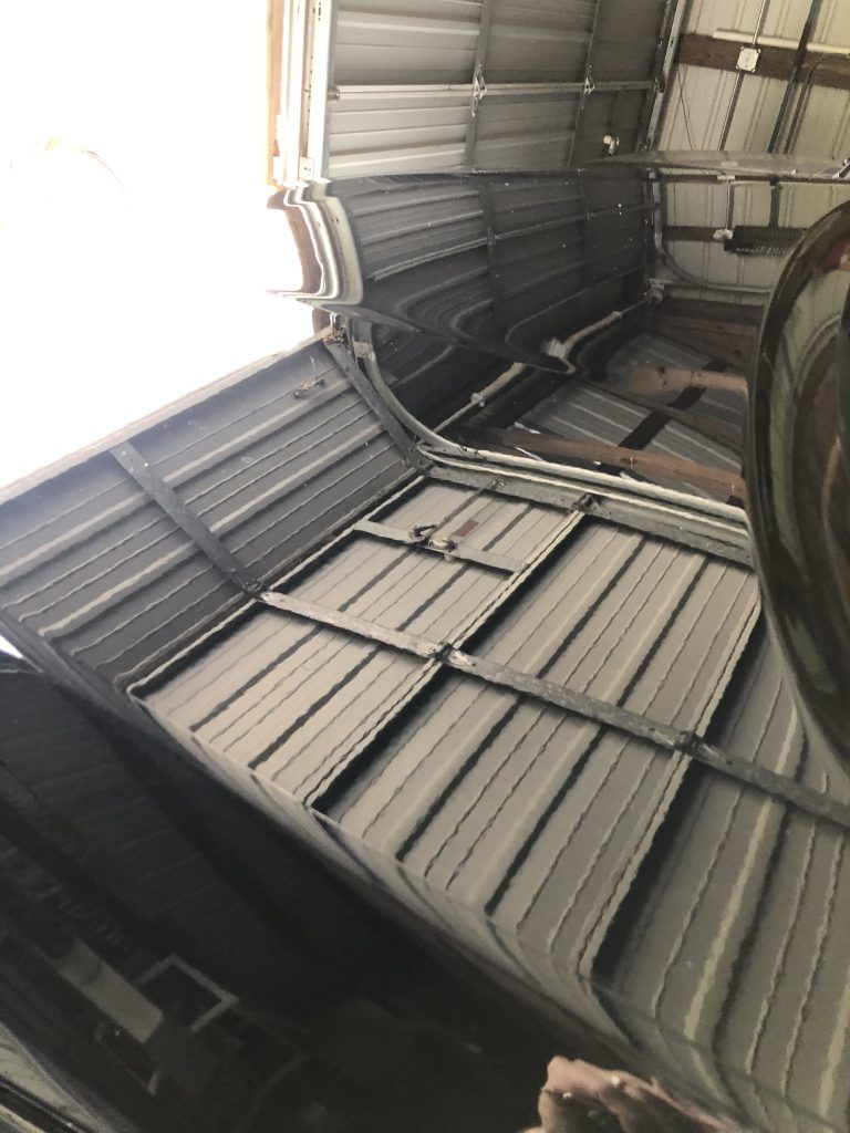 A car is parked in a garage with the hood open.