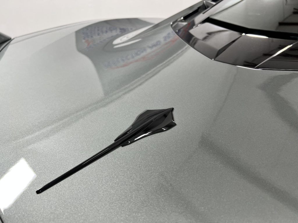 A close up of a car hood with a antenna on it