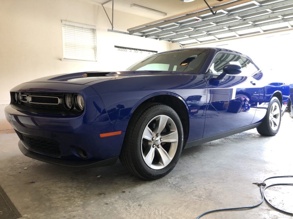 A blue dodge challenger is parked in a garage.