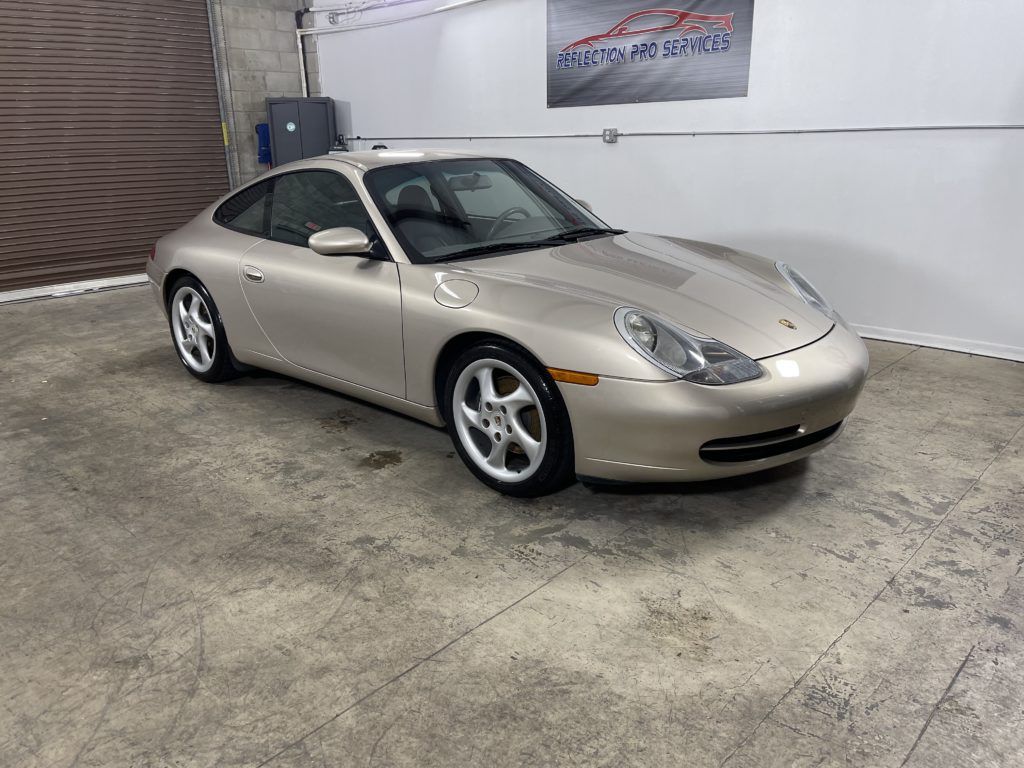 A silver porsche 911 is parked in a garage.