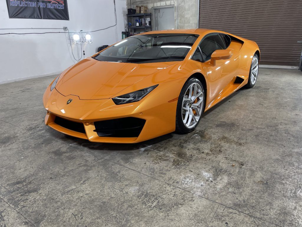 An orange lamborghini huracan is parked in a garage.
