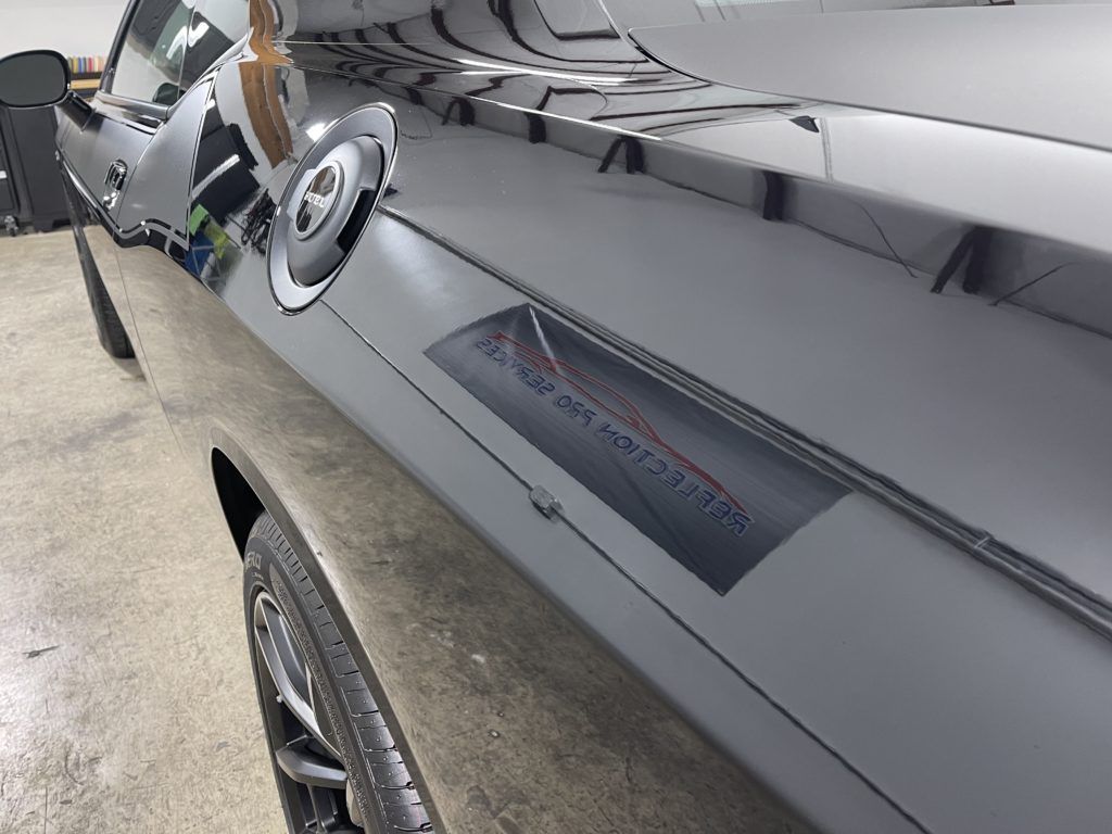 A black car is parked in a garage with a sticker on the side that says ' almost done '