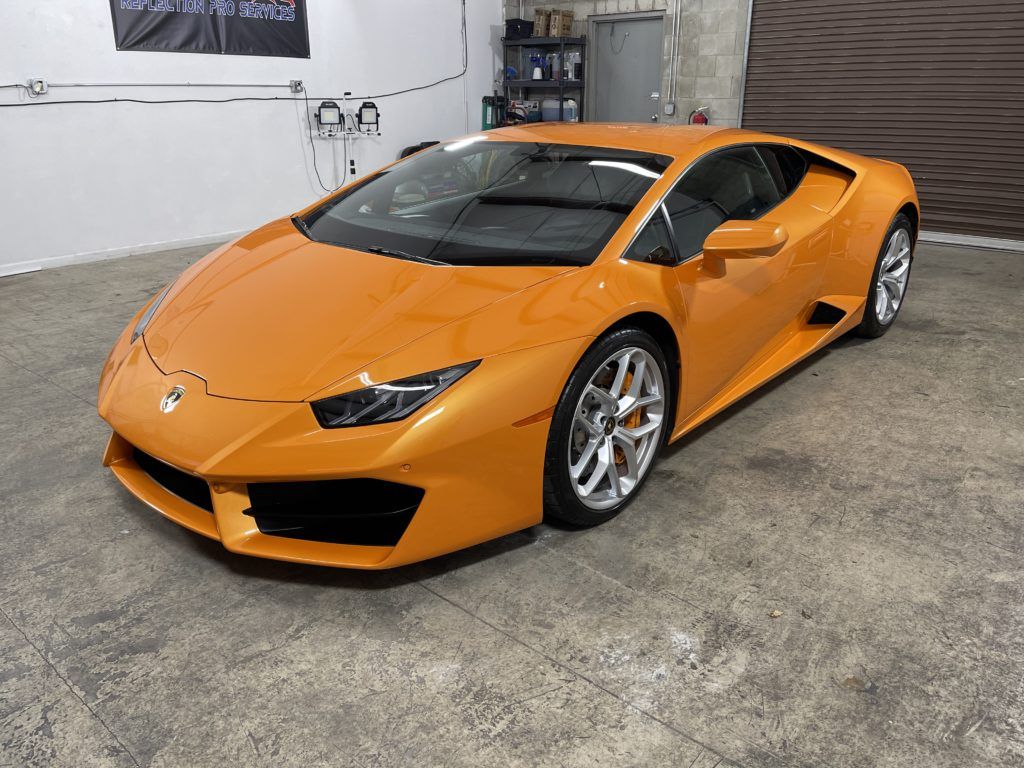 An orange lamborghini huracan is parked in a garage.