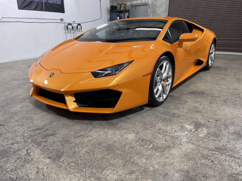 An orange lamborghini huracan is parked in a garage.