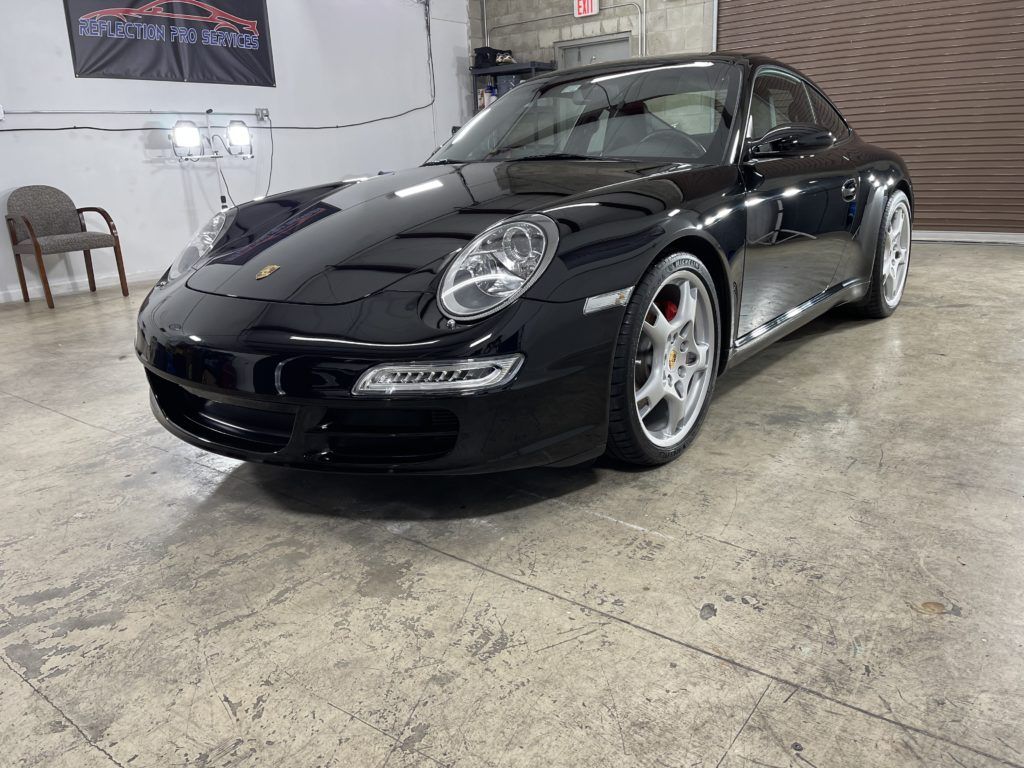 A black porsche 911 is parked in a garage.