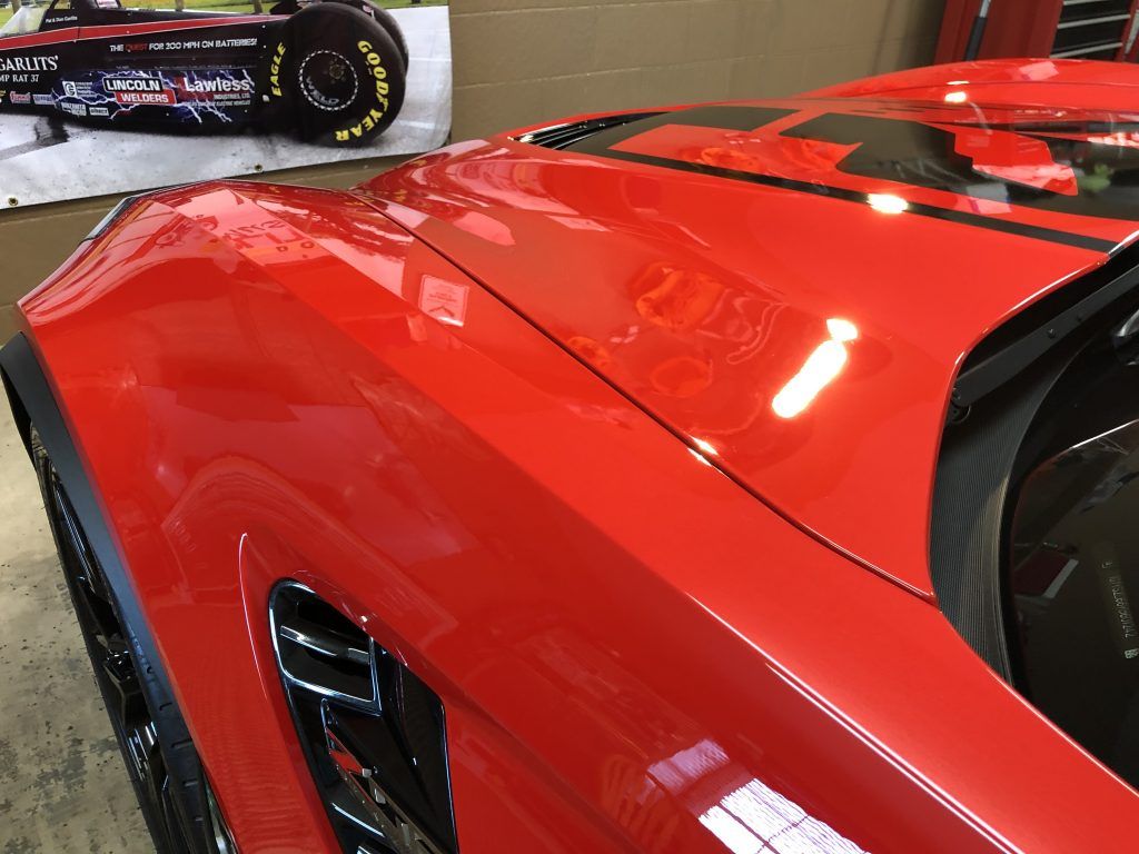 A red sports car is parked next to a model race car