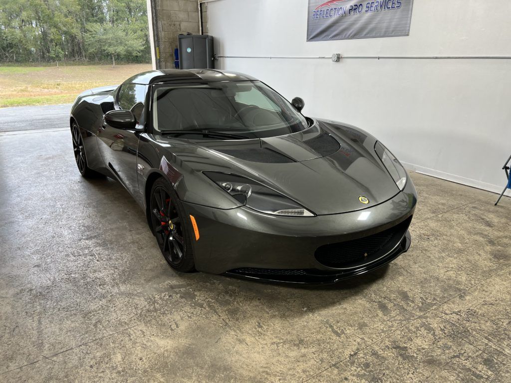 A gray sports car is parked in a garage.
