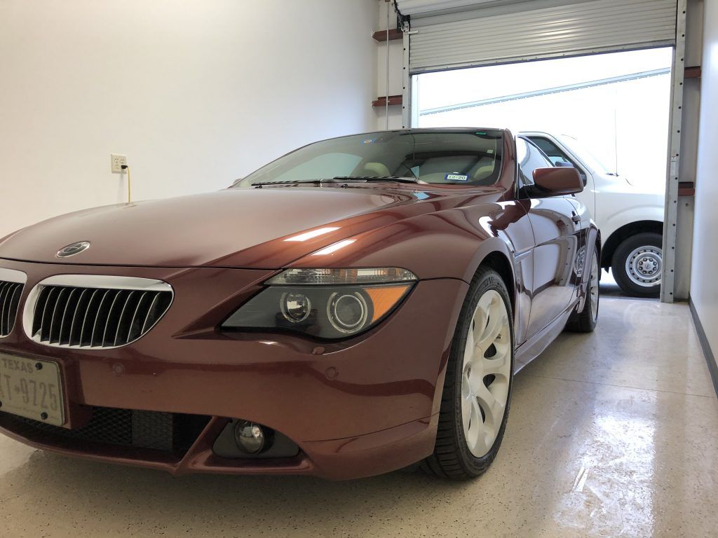 A red bmw is parked in a garage next to another car
