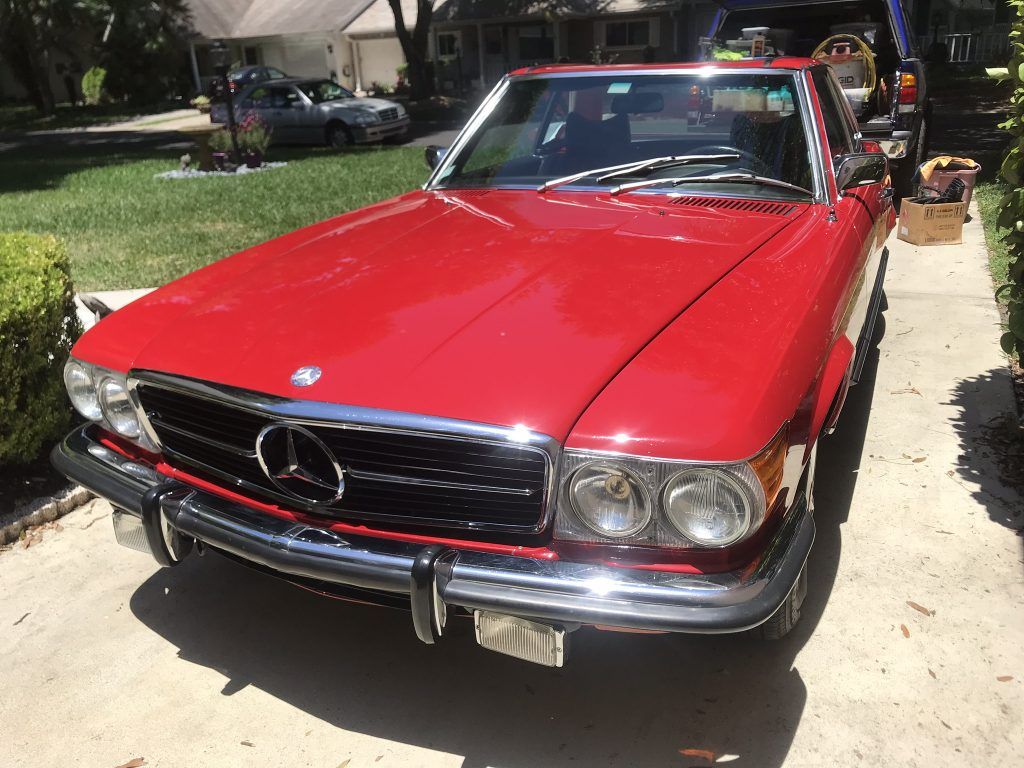 A red mercedes benz sl500 is parked in a driveway.