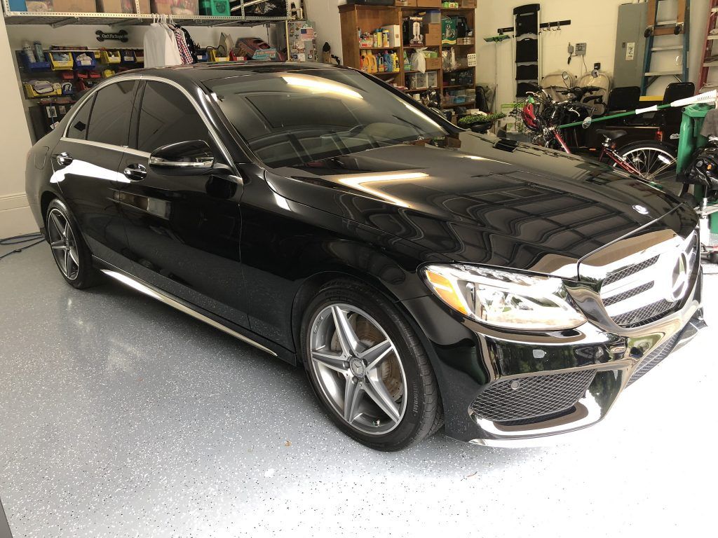 A black mercedes benz is parked in a garage.