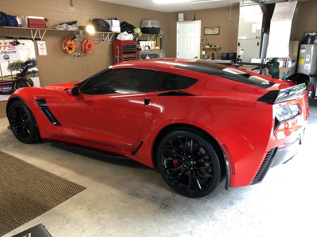 A red sports car is parked in a garage.