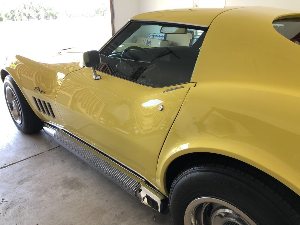 A yellow corvette is parked in a garage.