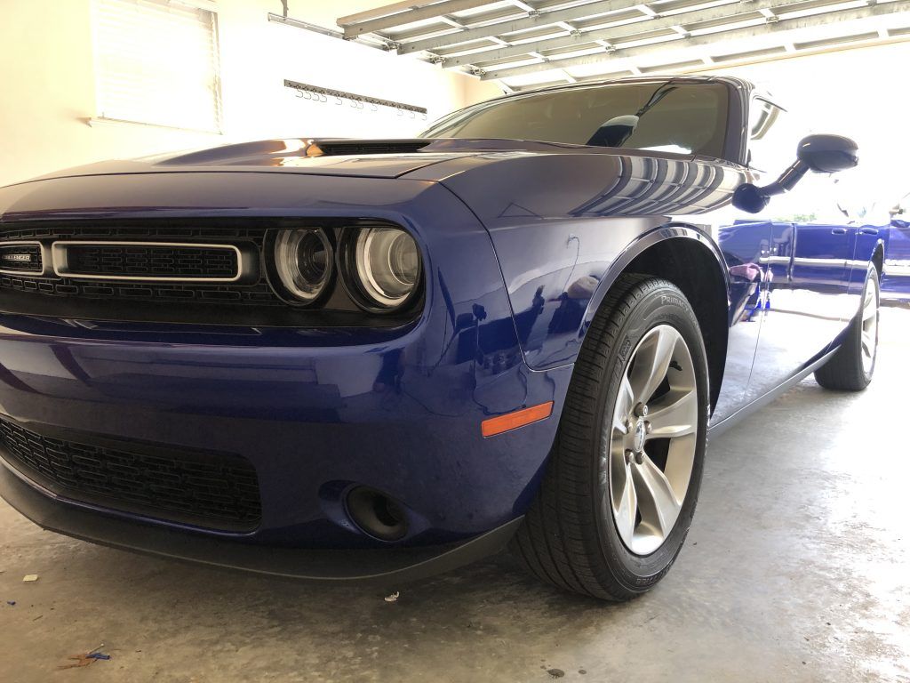 A blue dodge challenger is parked in a garage.