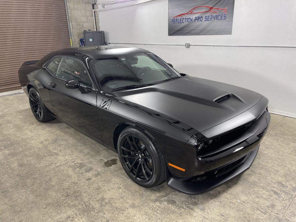 A black dodge challenger is parked in a garage.
