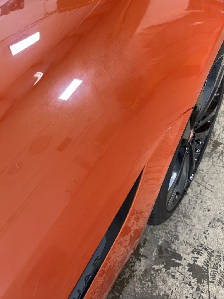 A close up of the side of an orange car.