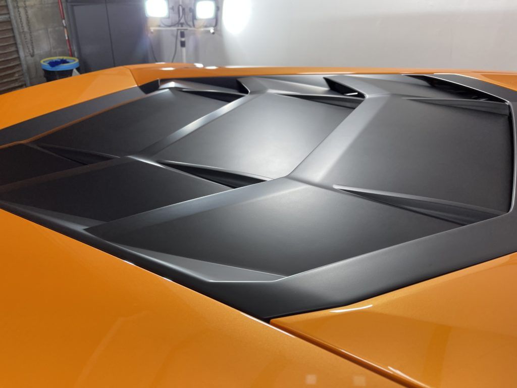 A close up of the hood of an orange sports car