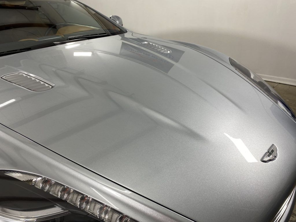 A close up of the hood of a silver car in a garage.