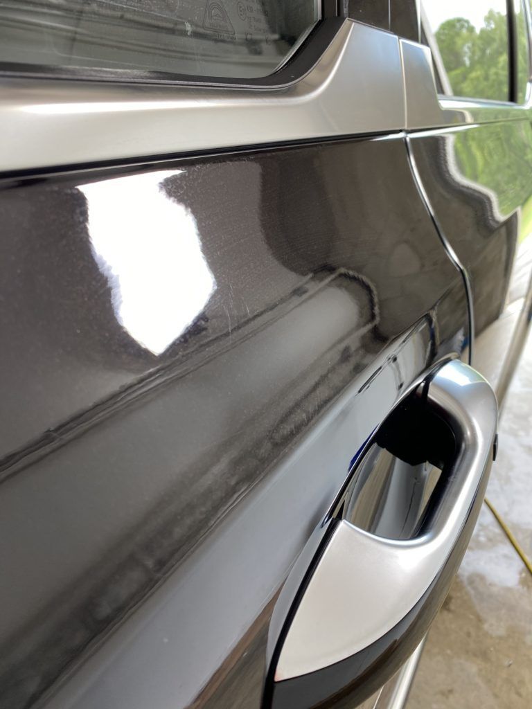 A close up of the door handle of a black car.