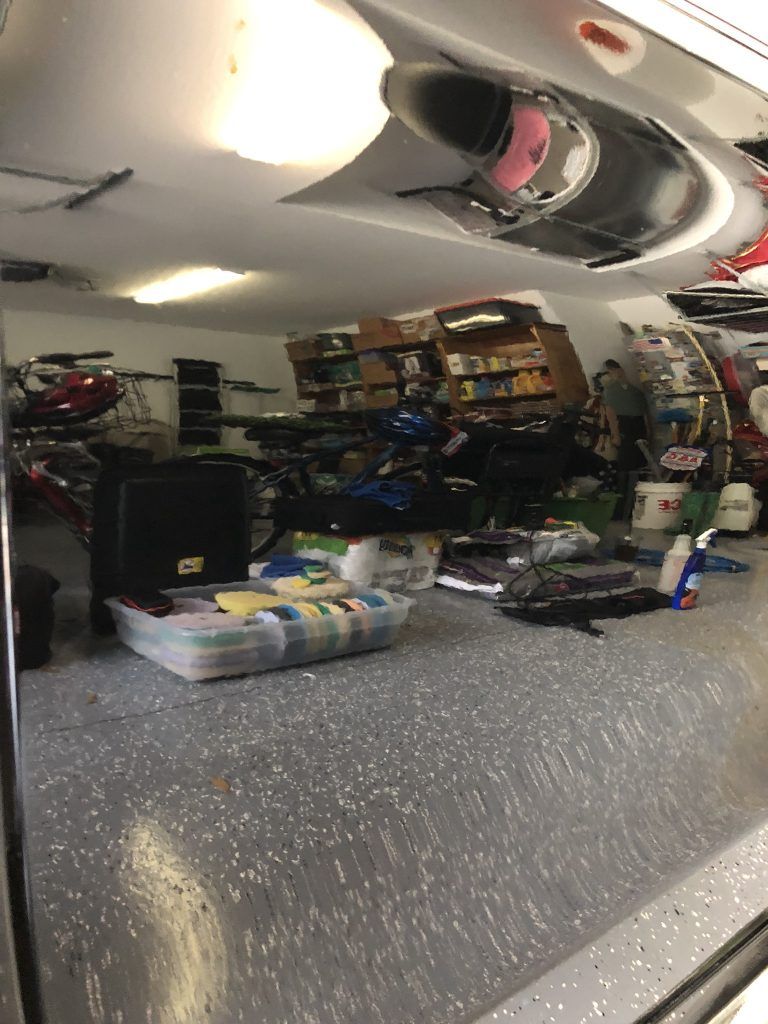 A garage filled with lots of items and a reflection of a car in the mirror.