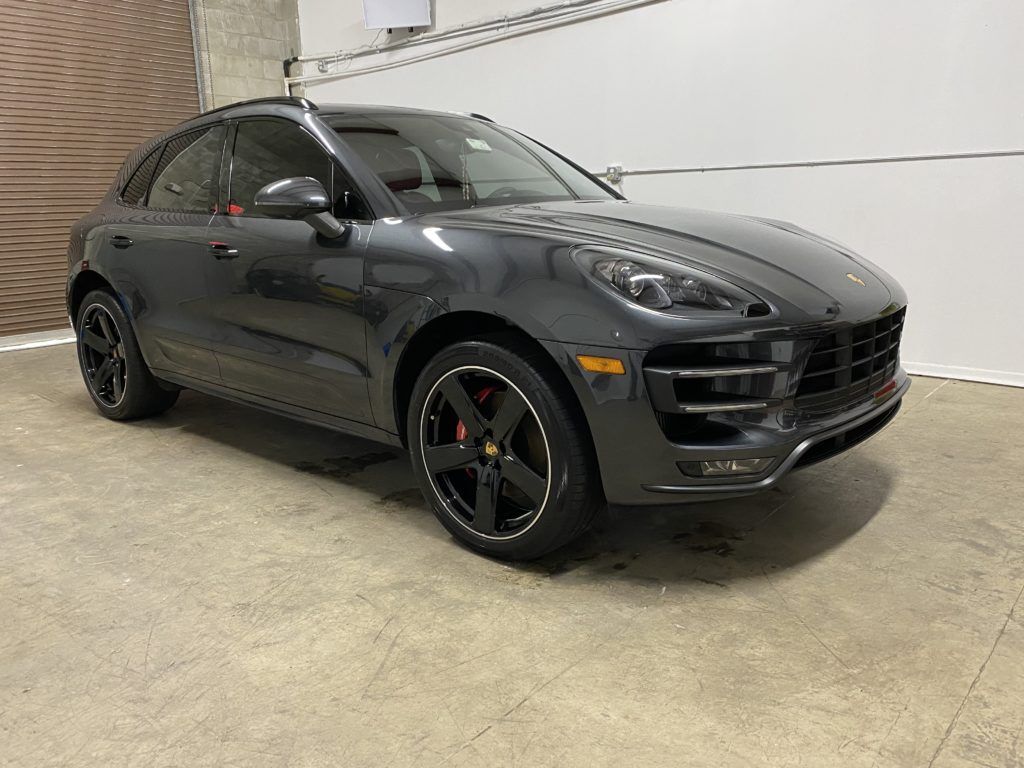 A gray porsche macan turbo is parked in a garage.