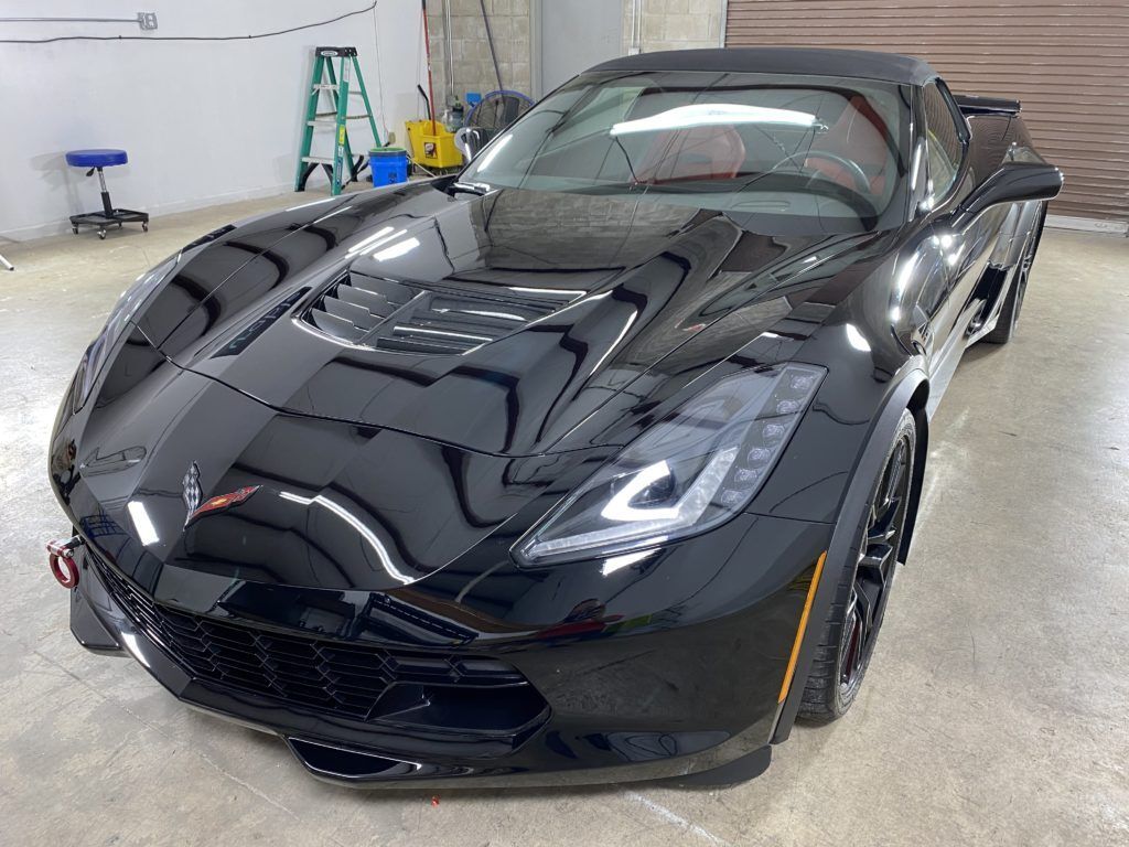 A black corvette convertible is parked in a garage.