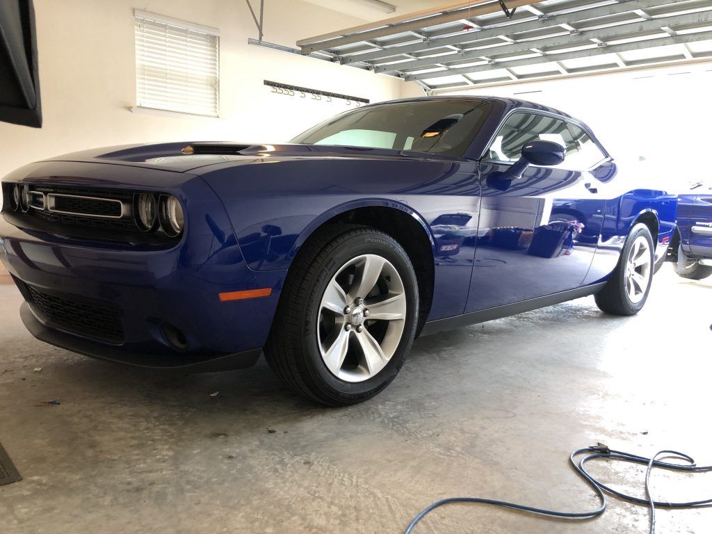 A blue dodge challenger is parked in a garage.