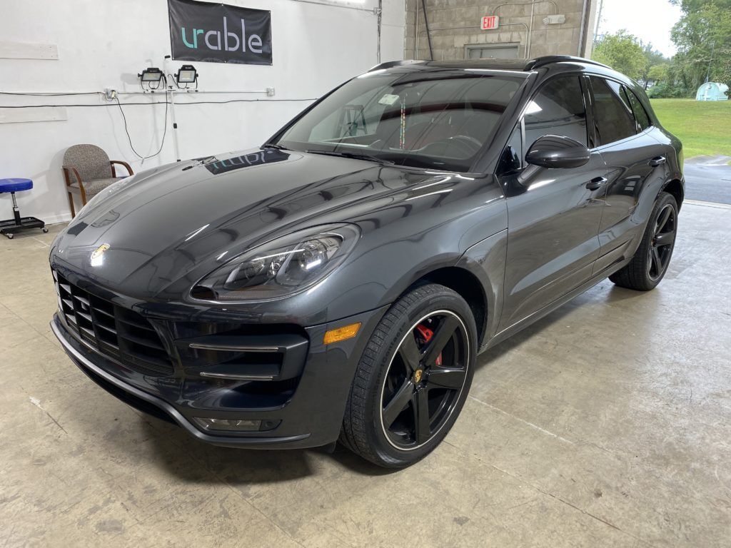 A black porsche macan turbo is parked in a garage.