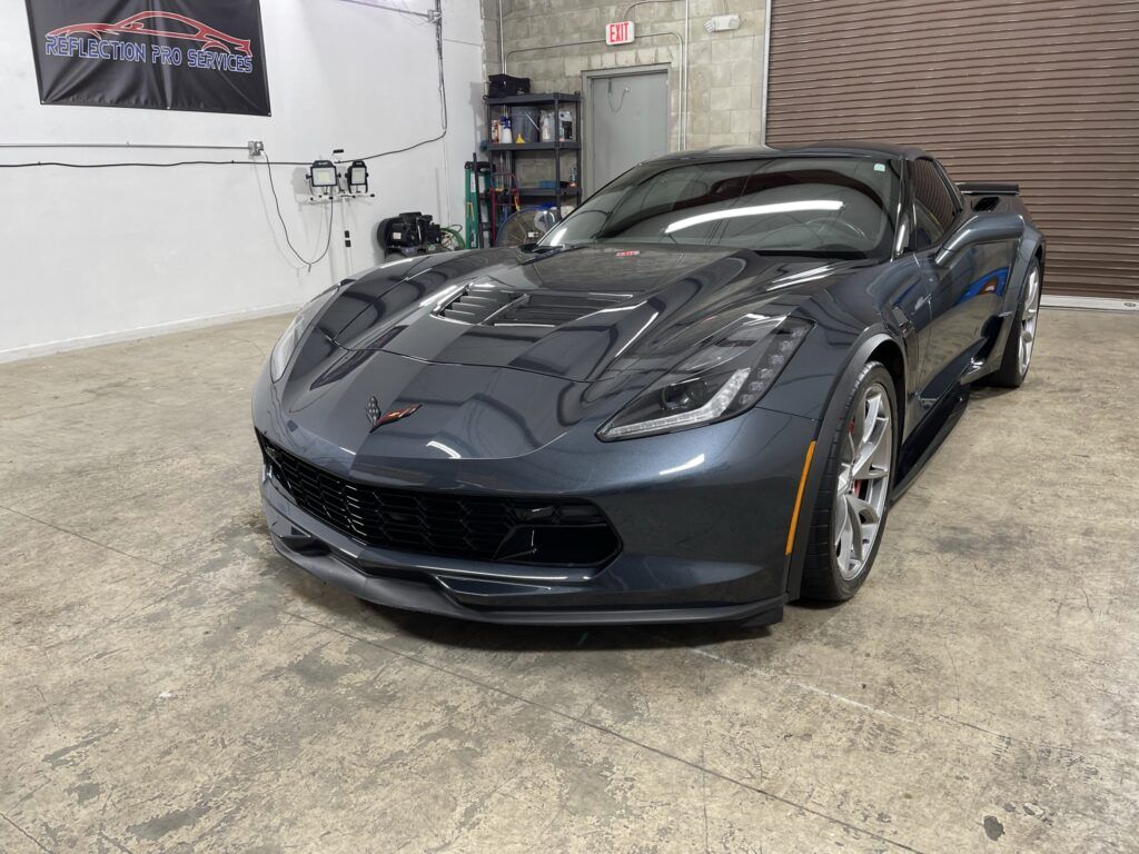 A black corvette is parked in a garage.