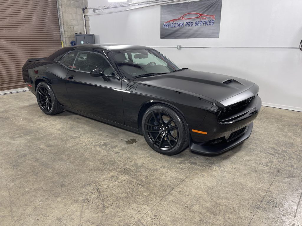 A black dodge challenger is parked in a garage.