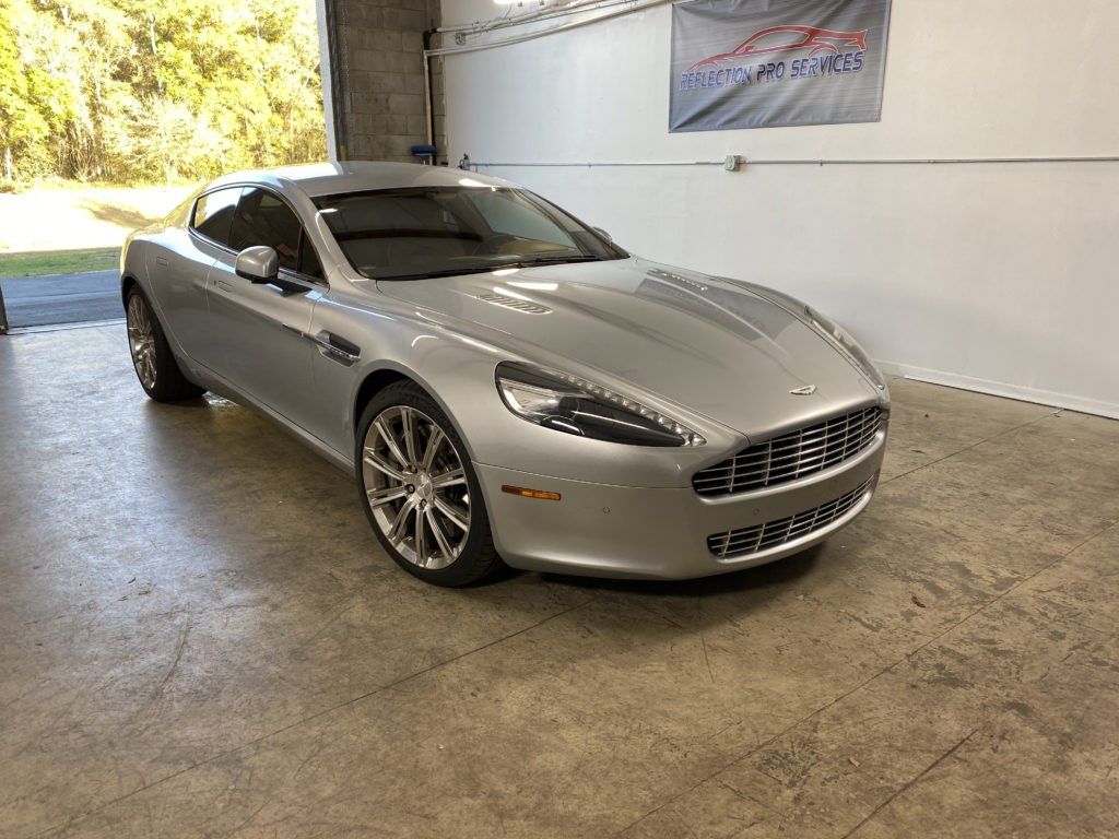 A silver aston martin sports car is parked in a garage.