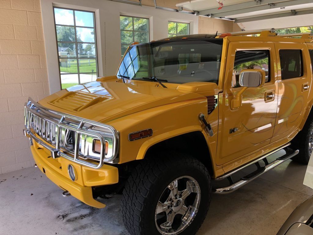 A yellow hummer h2 is parked in a garage.