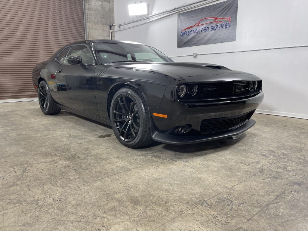 A black dodge challenger is parked in a garage.