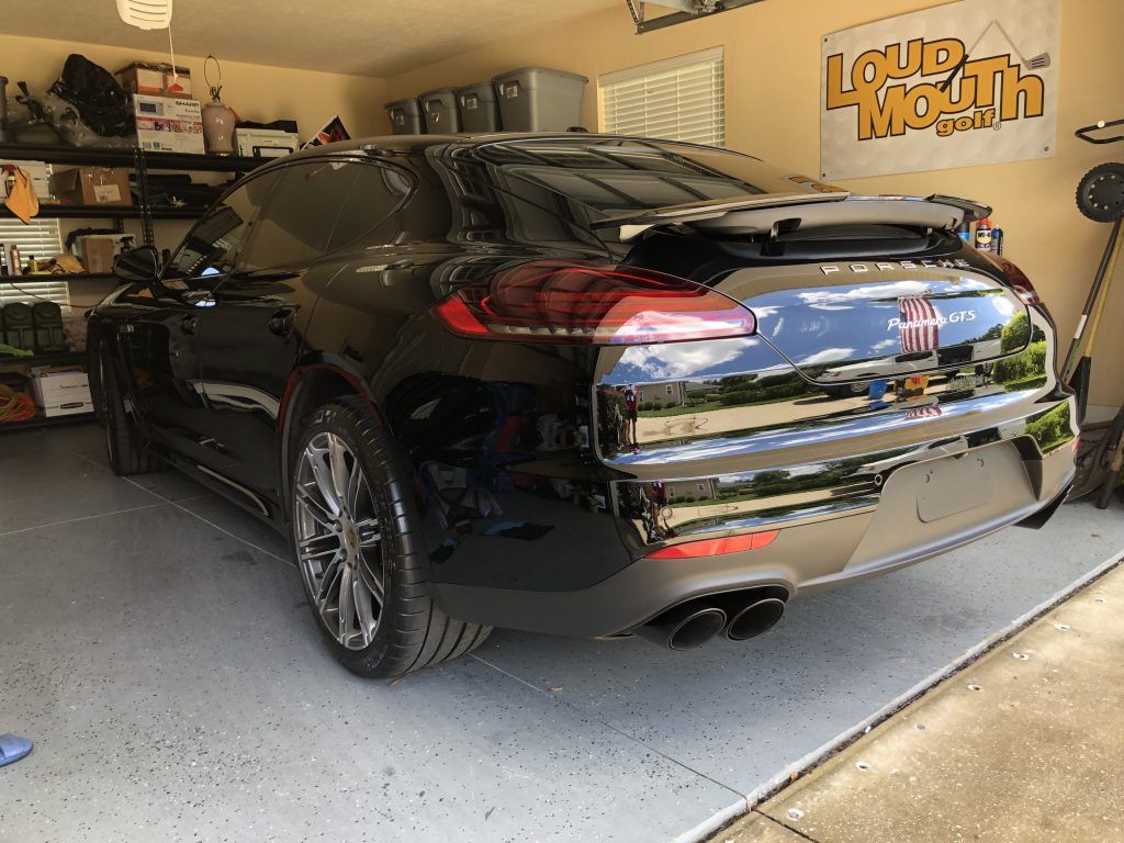 A black car is parked in a garage next to a sign that says loud mouth.