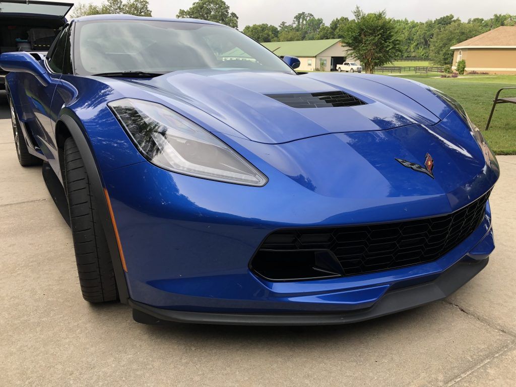 A blue corvette is parked on the side of the road.