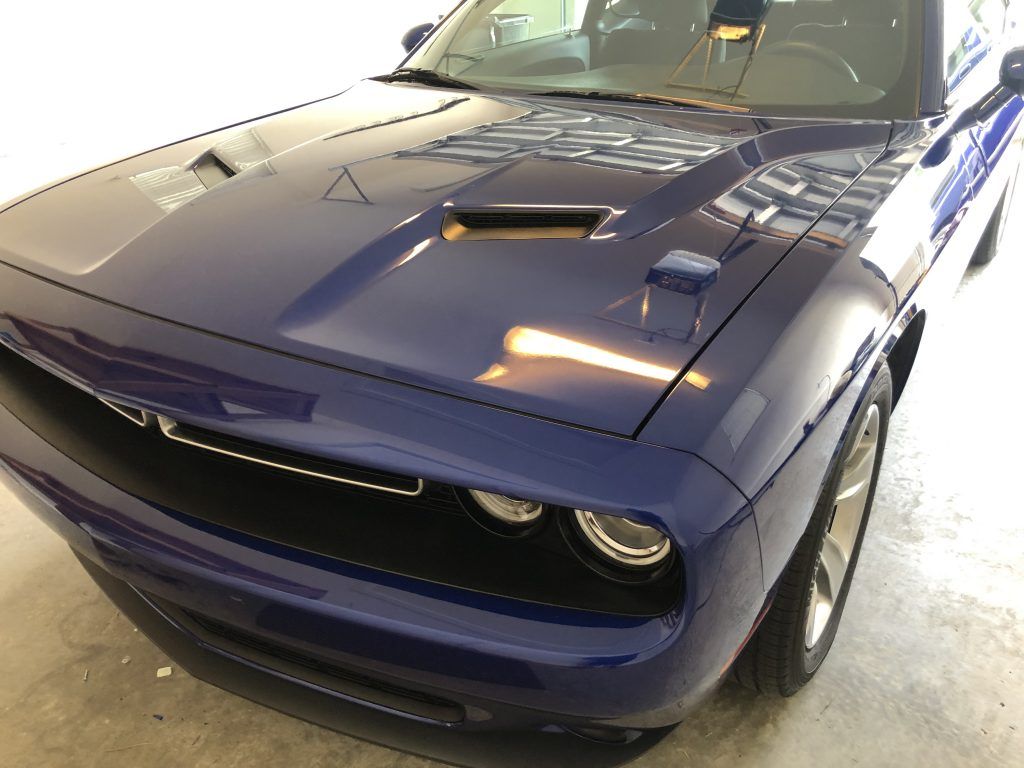 A blue dodge challenger is parked in a garage.
